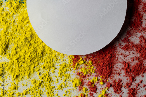Close up of red and yellow coloured powder and white circle with copy space on white background