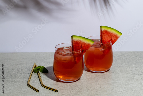 Glasses with drinks and watermelon in grey space