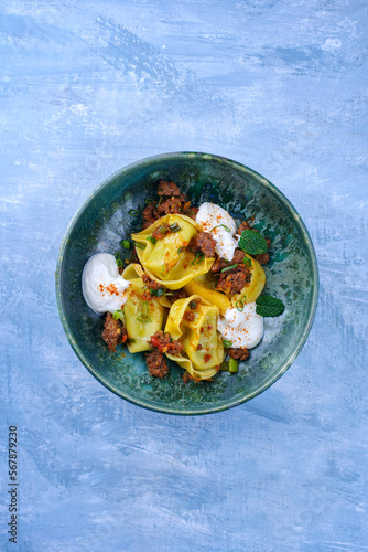 Traditional oriental manti dumplings with spicy minced meat and yogurt served as top view in a Nordic design plate with text free space photo