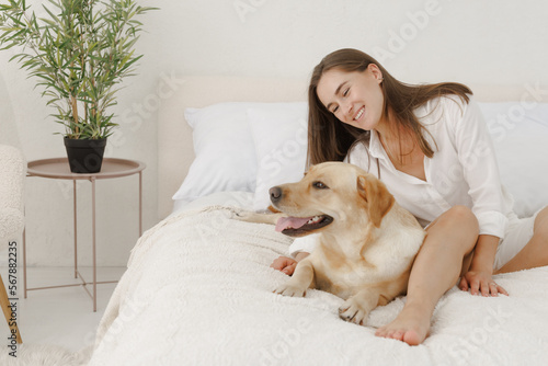 girl in white clothes with dog labrador playing at home