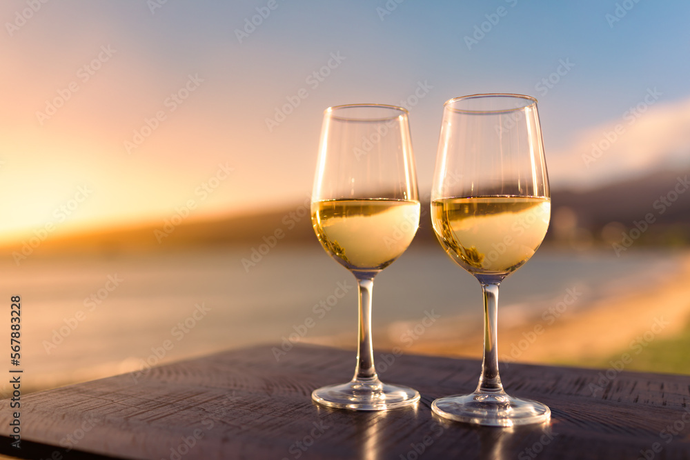 Romantic summertime lifestyle beach side getaway for two. Pair of wine glasses and tropical ocean view 