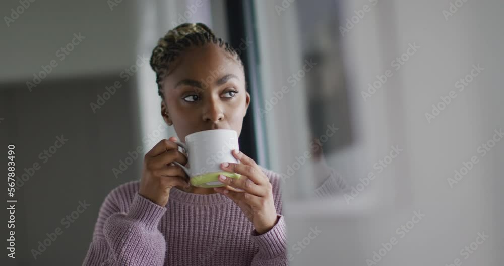 Thoughtful african american woman drinking coffee and looking outside window Thoughtful african american woman drinking coffee and looking outside window