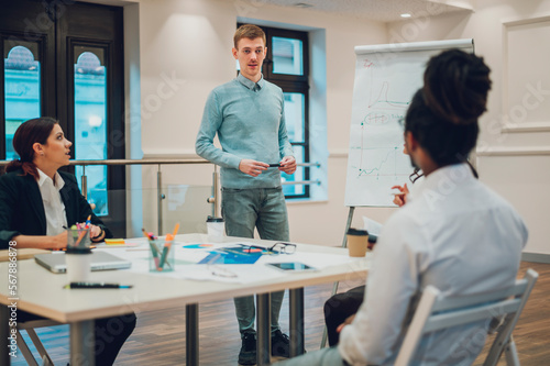 Redhead businessman holding a meeting to his diverse colleagues in an office