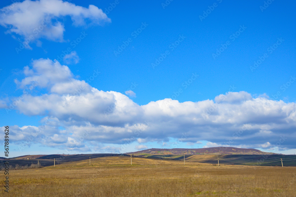 Plains, hills and blue sky with white clouds.