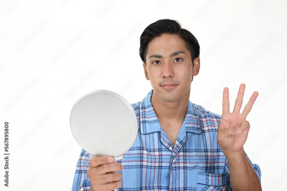 手鏡を持つパジャマ姿の男性