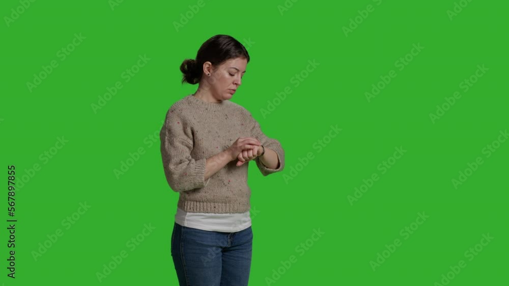 Side view of person running late and checking time on wristwatch, being punctual and waiting on camera. Young adult worrying and being impatient, looking at watch over greenscreen background.