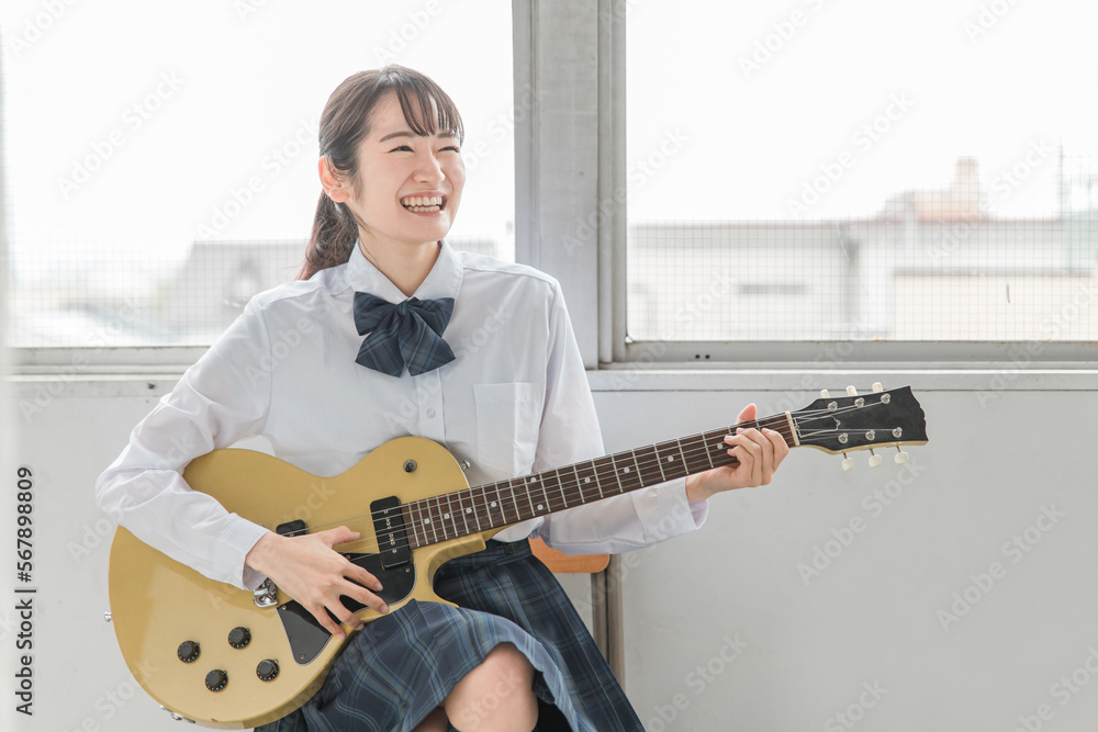 Fototapeta premium 学校の教室で楽器・ギターの演奏をする軽音部・吹奏楽部の高校生・中学生・女子高生（制服・バンド） 
