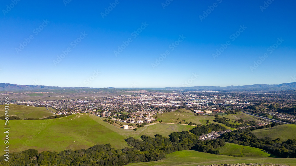 Naklejka premium Aerial photos over the Dublin Hills in Dublin, California with a city in the background with a blue sky