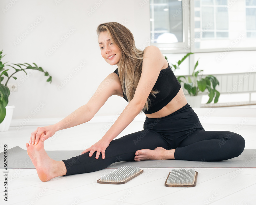 Caucasian woman sits on yoga mat after standing on sadhu nails. Caucasian woman sits on yoga mat after standing on sadhu nails.