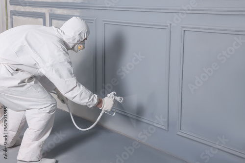 Foto Decorator dyeing wall in grey color with spray paint indoors, space for text