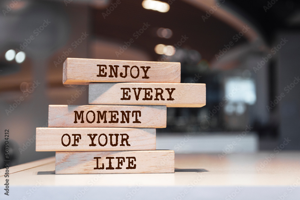 Wooden blocks with words 'Enjoy every moment of your life'.