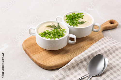 Bowls with tasty creamy soup of parsnip served on light grey background
