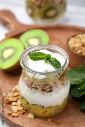 Delicious dessert with kiwi, yogurt and muesli on wooden board, closeup