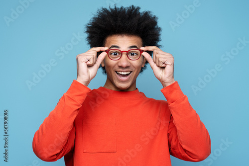 Portrait of attractive funny African American man wearing stylish isolated on blue background, vision concept. Young smiling nerd student looking at camera, education. Studio shot