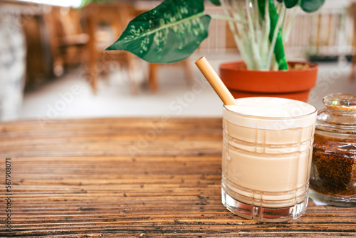 Fototapeta Naklejka Na Ścianę i Meble -  .An iced coffee on a bamboo table in a modern beach bar in Bali. A tropical plant in the background and copy space next to it