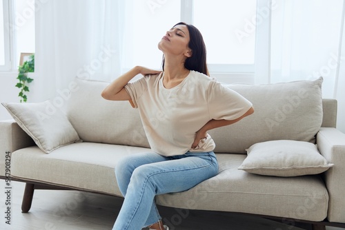 Woman sitting on sofa at home back and lower back pain, protrusion, back problems after 30 years