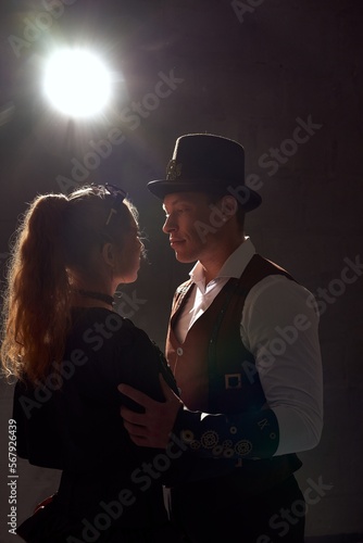 Obraz na płótnie Couple in vintage costumes dancing against glowing lamp