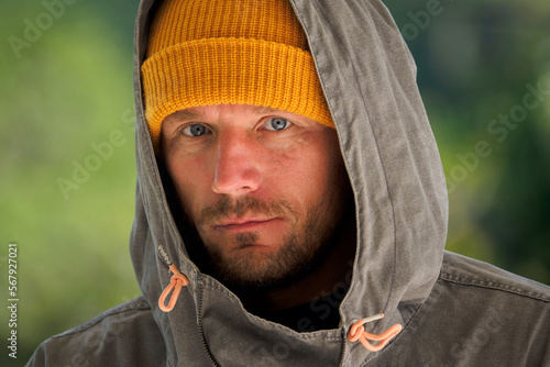 Portrait of contemplative  man wearing gray hoodie, yellow beanie hat. Cold weather concept. photo