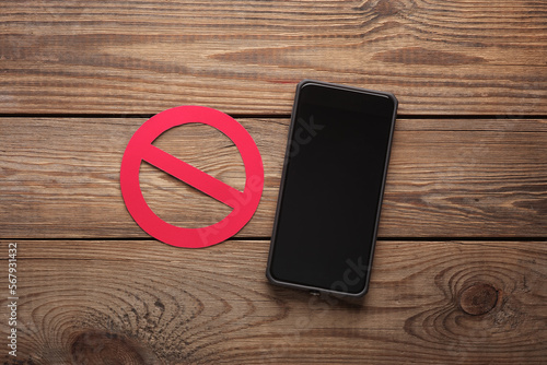 Smartphone with prohibition sign on a wooden table. Eco concept photo