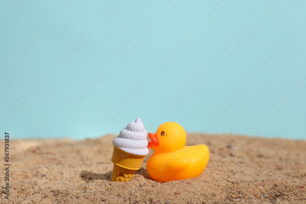 Obraz premium Rubber duck with ice cream on the sand. Beach holiday, summer time