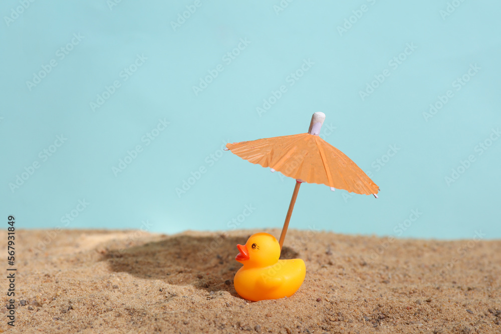 Rubber duck with ubrella on the sand. Beach holiday, summer time Rubber duck with ubrella on the sand. Beach holiday, summer time