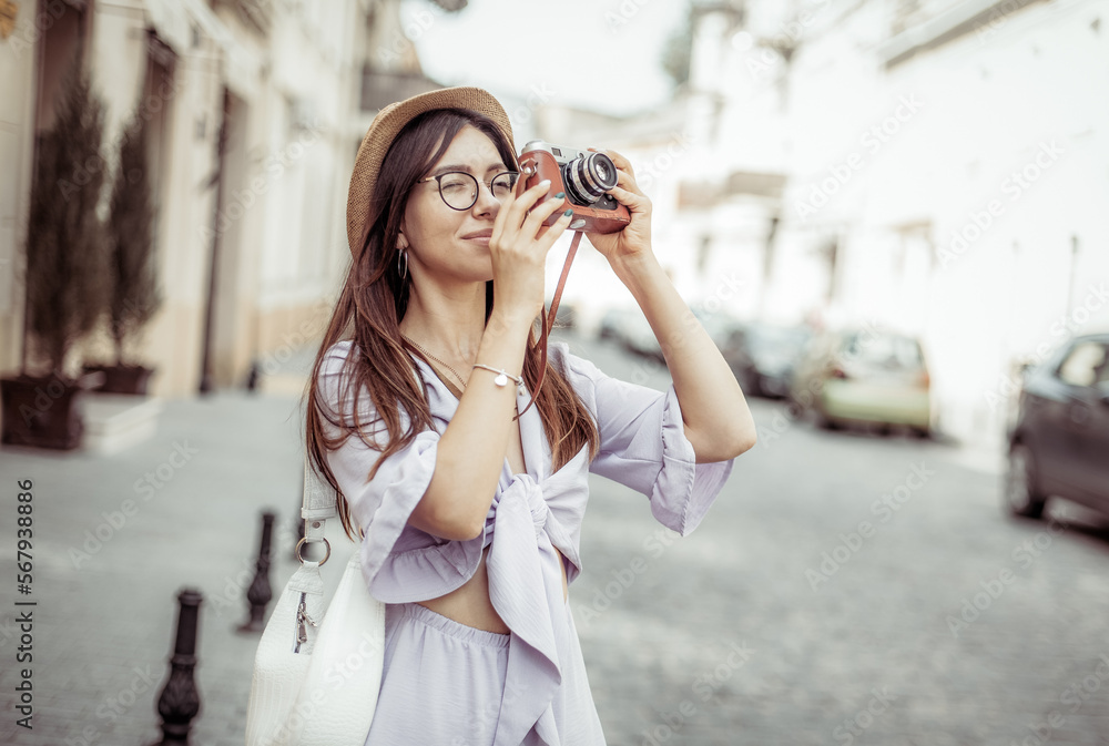 Beautiful young woman tourist photographs urban architecture on a European street. Travel concept