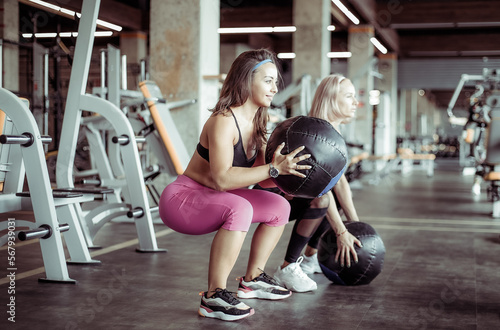 Two athletic women exercise with medicine balls in the gym. Functional training