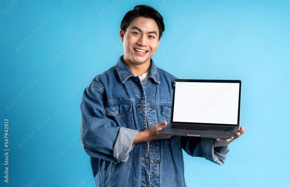 Young asian man using laptop on a blue background Young asian man using laptop on a blue background