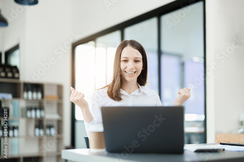 Excited businesswoman using computer laptop while in office, business concepts.