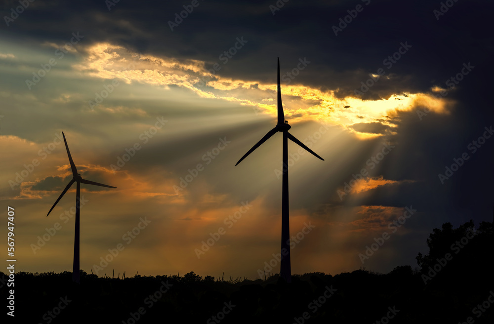 Obraz premium Dark storm clouds over silhouette of two wind turbines in the field, copy space