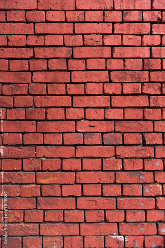 Bright red brick wall background. Red brick texture. Old handmade brick. Brick wall with broken bricks. vertical photo