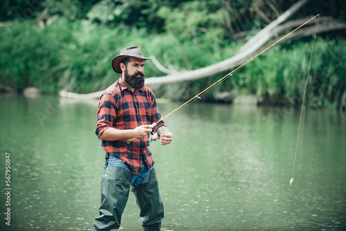 Young bearded man fishing at a lake or river. Flyfishing.