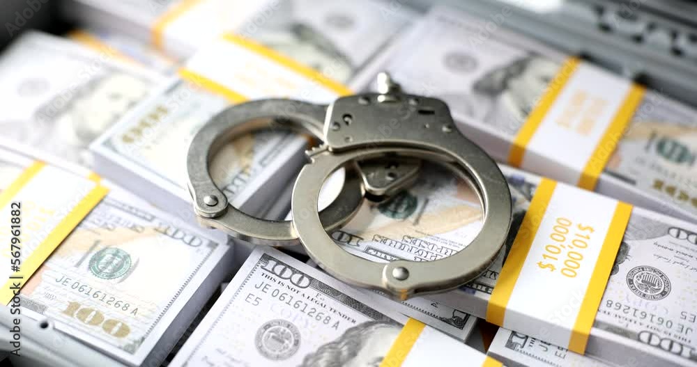 Police handcuffs lie on many dollar bills Police handcuffs lie on many dollar bills