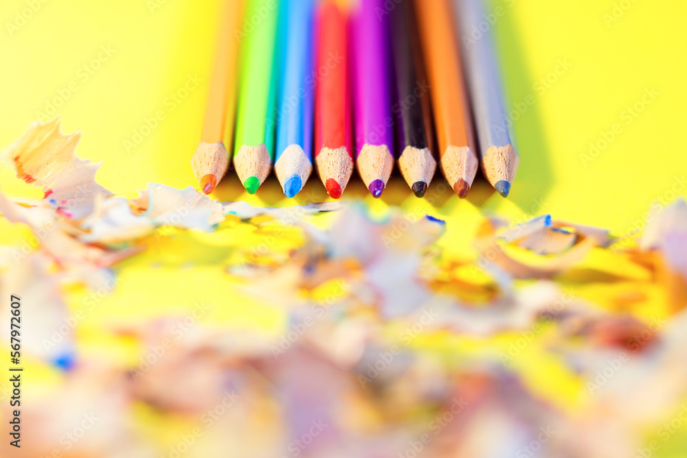 Chiseled colored pencils lie beautifully on a yellow background. Garbage from chiseled pencils. Preparation for school. Drawing Tools Chiseled colored pencils lie beautifully on a yellow background. Garbage from chiseled pencils. Preparation for school. Drawing Tools