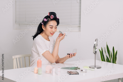 Daily makeup routine, Asian young women looks in the mirror during putting makeup on her face.