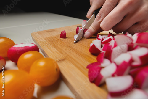 Pink radish is cut with a knife in the kitchen. concept of healthy food salad, vegetables. closeup fingers and sliced radish