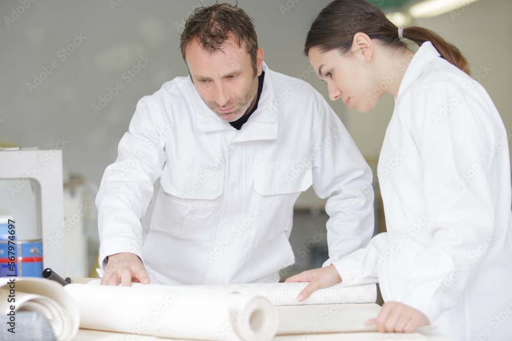 Obraz premium female apprentice learning wallpapering techniques