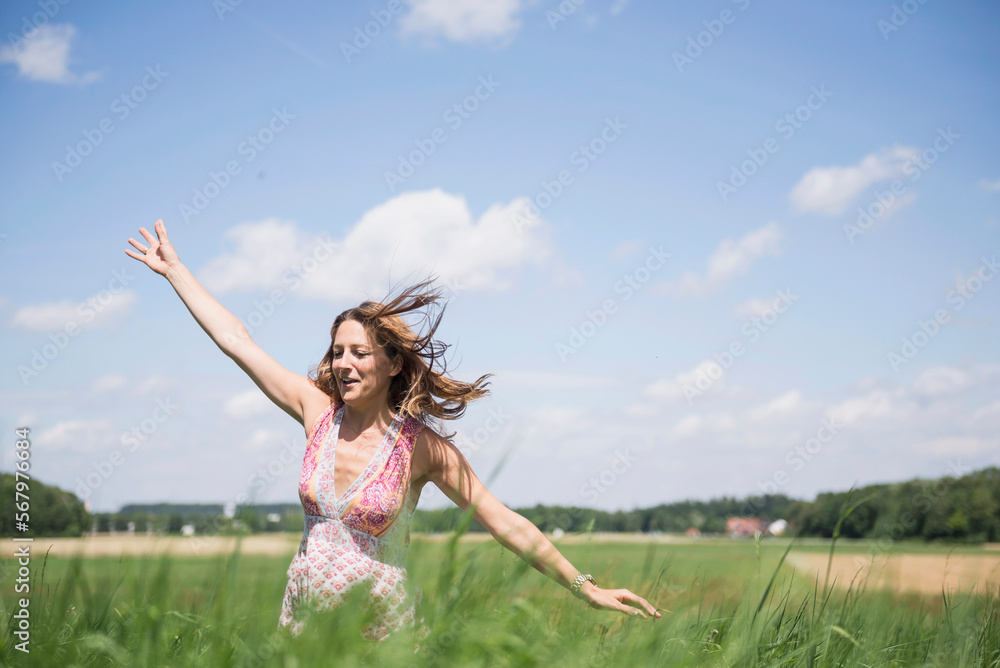 Happy woman enjoying with arms raised on a meadow in the countryside, Bavaria, Germany Happy woman enjoying with arms raised on a meadow in the countryside, Bavaria, Germany