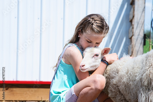Blond tween girl hugging a lamb. photo