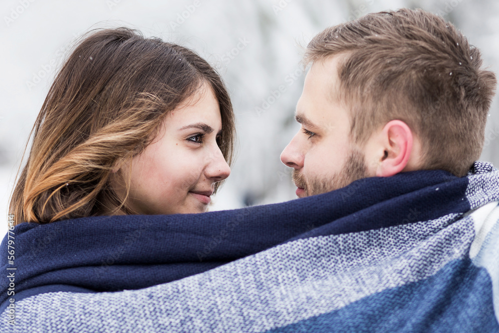 pair of lovers are wrapped in a blue scarf, among the snow park pair of lovers are wrapped in a blue scarf, among the snow park