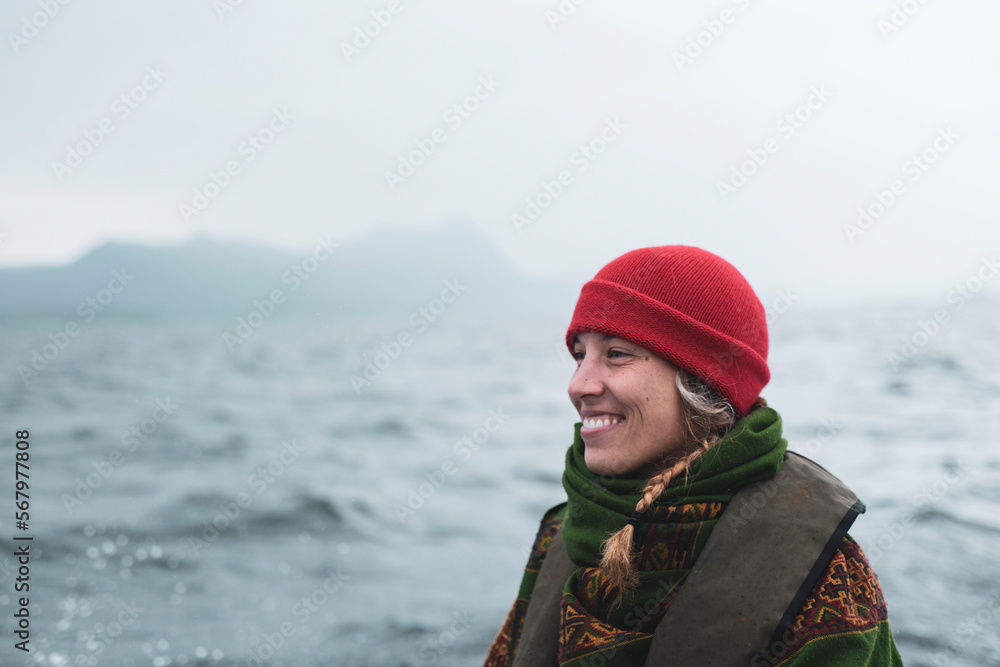 Beautiful woman in red hat smiles on edge of boat through islands Beautiful woman in red hat smiles on edge of boat through islands