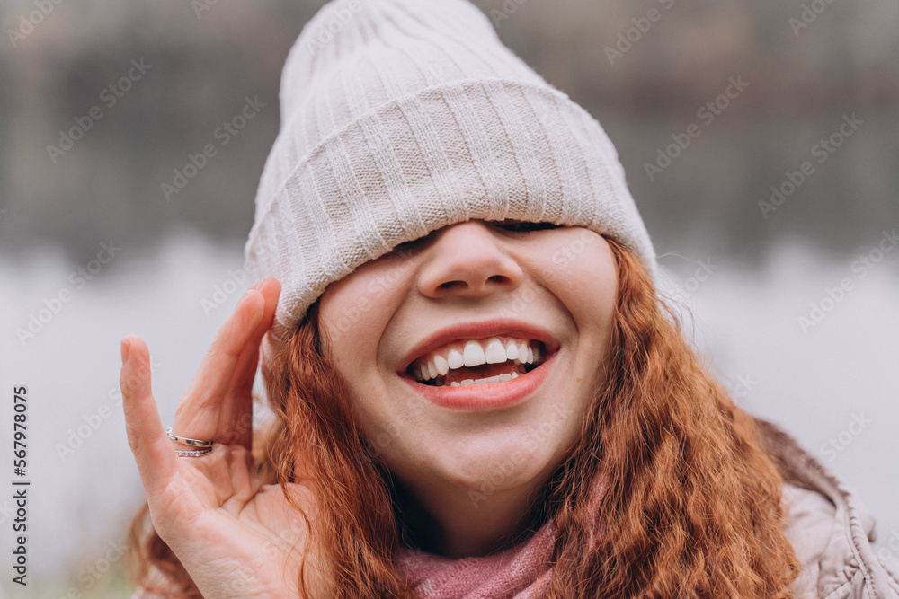 Curly redhead woman 30-35 with a cap over her eyes laughs Curly redhead woman 30-35 with a cap over her eyes laughs