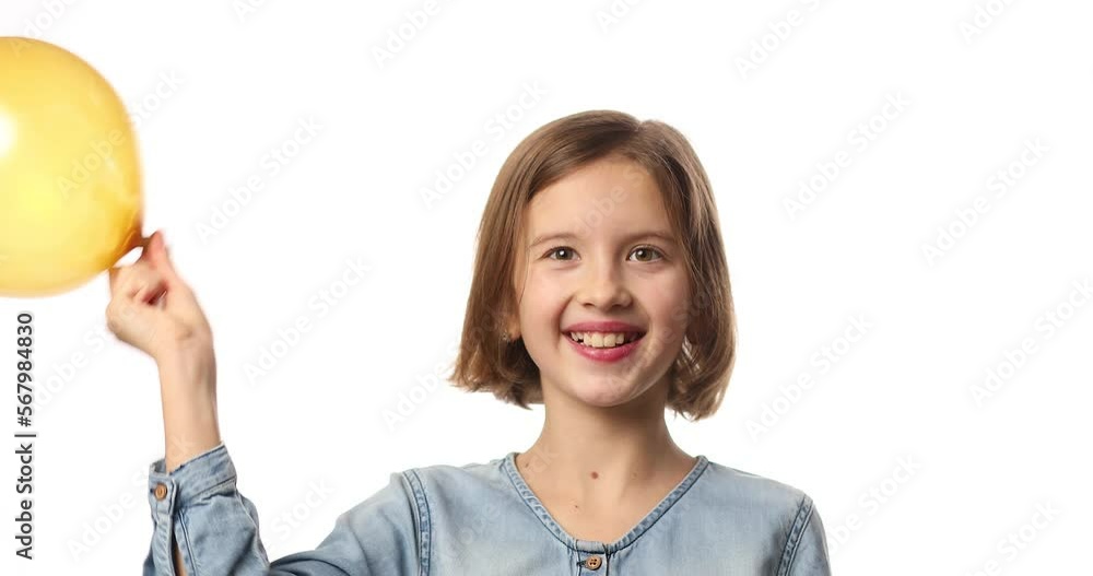 Pretty little girl in casual denim dress blowing, inflate yellow balloon Pretty little girl in casual denim dress blowing, inflate yellow balloon
