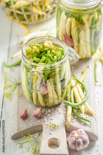 Healthy canned yellow and green beans in jar with herbs.