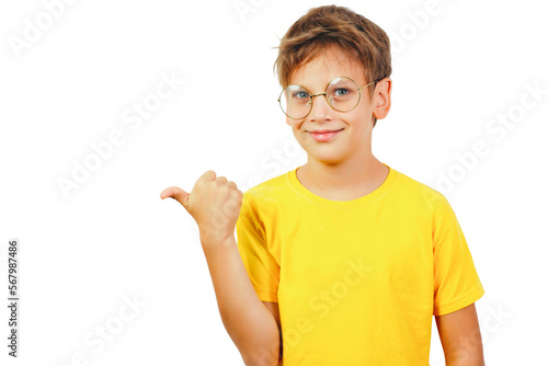 Smiling teenager in glasses and a yellow t-shirt points his thumb to the left. Isolated on white background. © Oleg Kozlovskiy