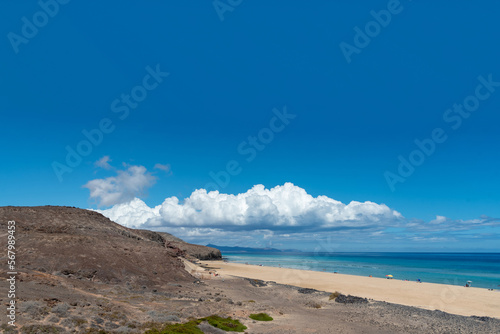 Vista panorámica de la impresionante playa de Jandia en Fuerteventura con arena blanca, mar turquesa, rodeada de un paisaje volcánico y rocoso en la costa de las islas Canaria © Safi