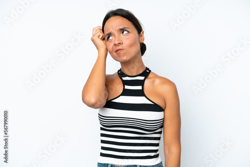 Young hispanic woman isolated on white background having doubts while scratching head © luismolinero