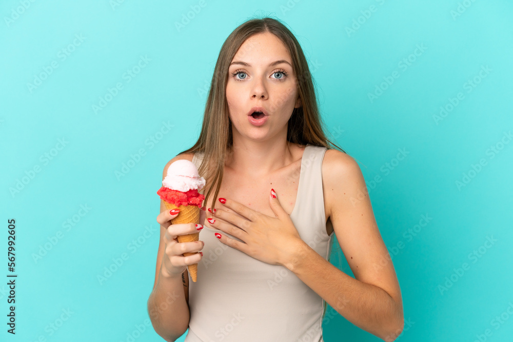 Young Lithuanian woman with cornet ice cream isolated on blue background surprised and shocked while looking right Young Lithuanian woman with cornet ice cream isolated on blue background surprised and shocked while looking right