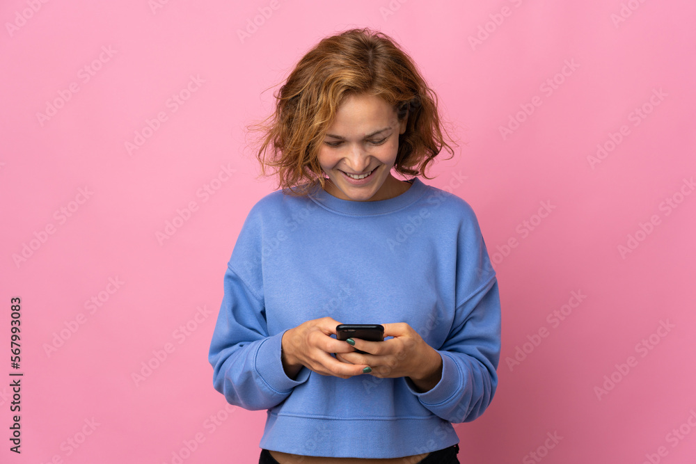 Young Georgian woman isolated on pink background sending a message with the mobile Young Georgian woman isolated on pink background sending a message with the mobile