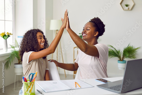 Happy excited african american woman teacher and her student teen girl high five to each other with smile. Joy for a successfully completed project. Teens education, support and friendship concept.